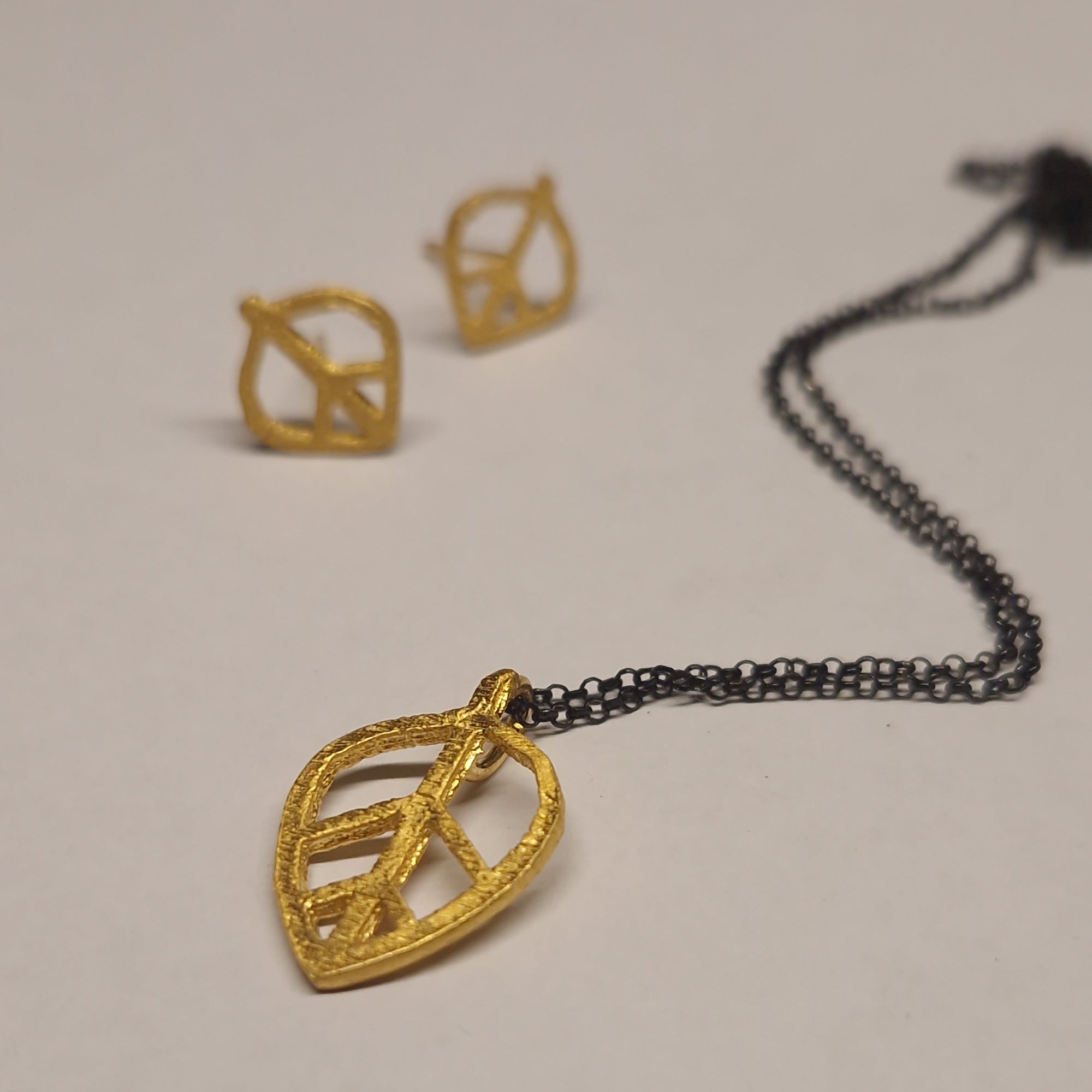 Gold necklace and earrings on a light gray background
