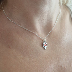 Silver necklace with a red pendant on a person's neck