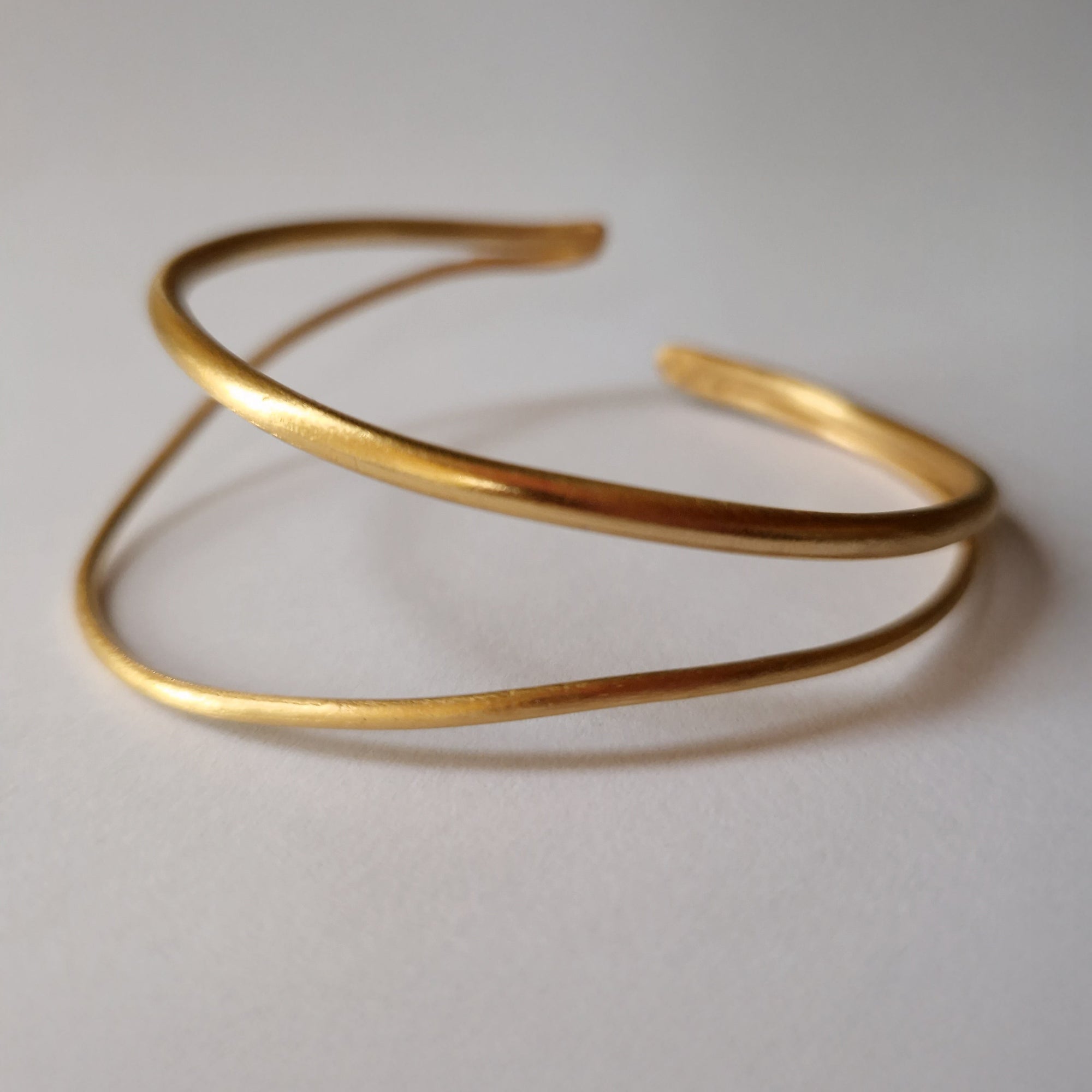 Gold bracelet on a light gray background