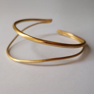 Gold bracelet on a light gray background