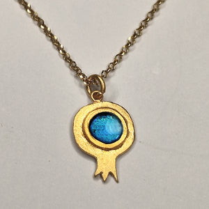 Gold necklace with a blue pendant on a light gray background
