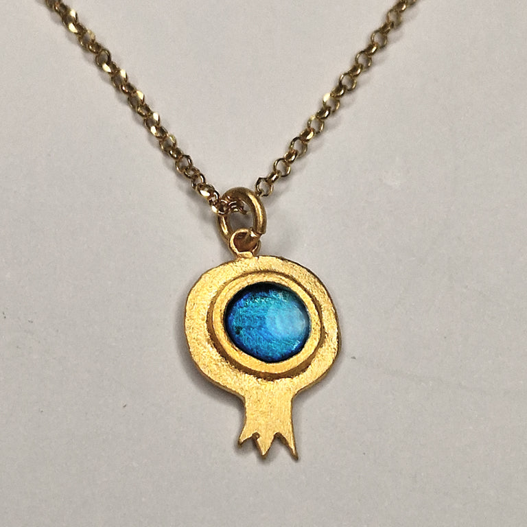 Gold necklace with a blue pendant on a light gray background