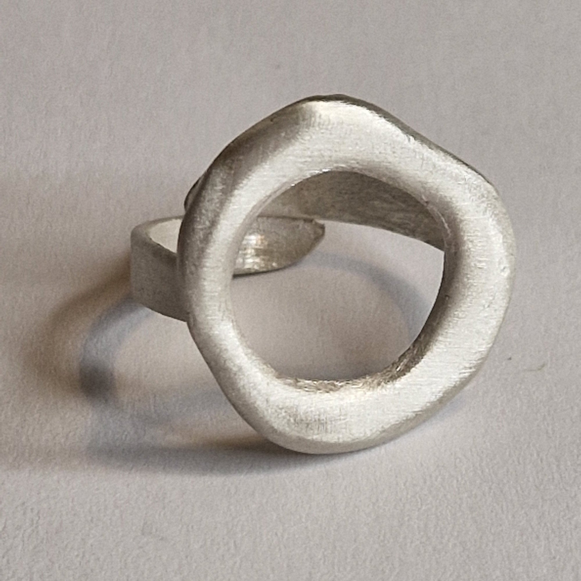 Silver ring with a unique design on a gray background