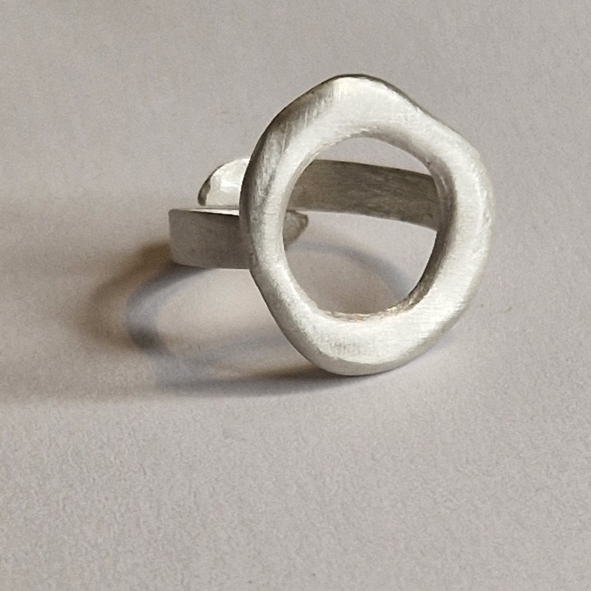 Silver ring with a unique design on a light gray background