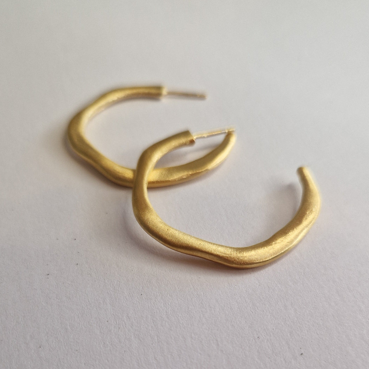 Gold hoop earrings on a light gray background