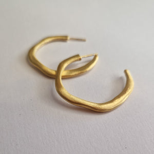 Gold hoop earrings on a light gray background