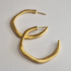 Gold hoop earrings on a light gray background
