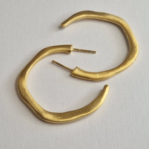 Pair of gold hoop earrings on a light gray background