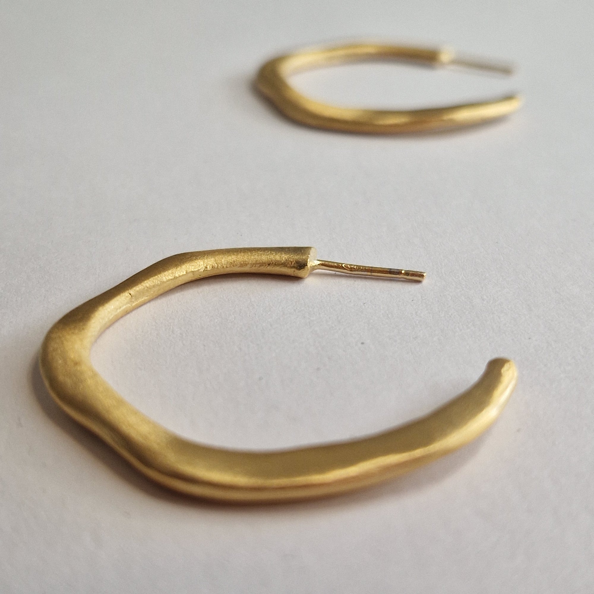 Gold hoop earrings on a light gray background