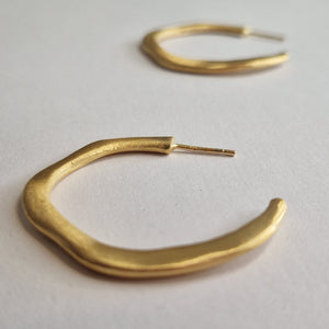 Gold hoop earrings on a light gray background
