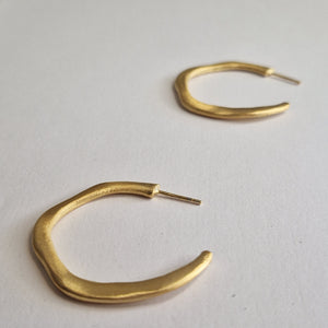Gold hoop earrings on a light gray background