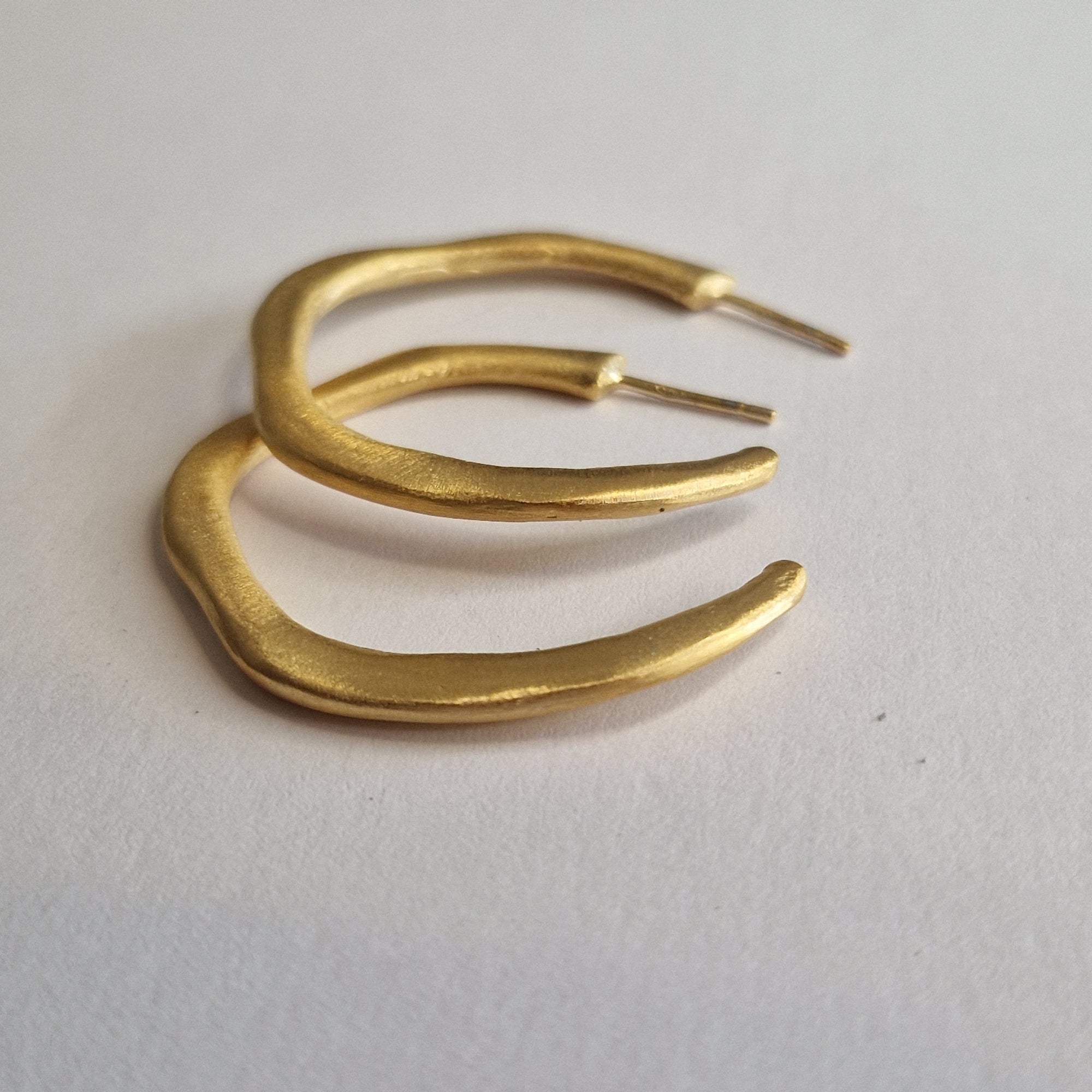 Pair of gold earrings on a light gray background