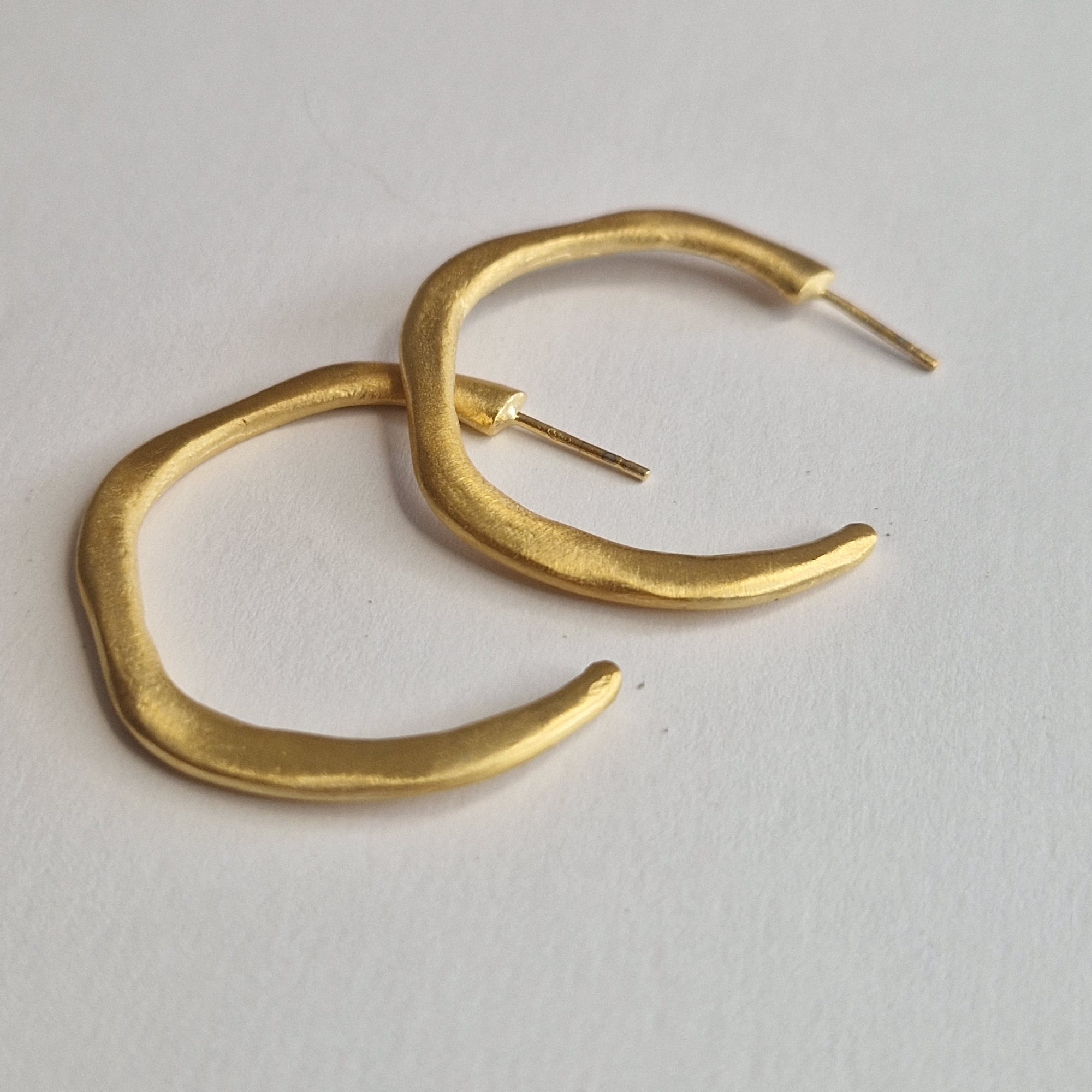 Gold hoop earrings on a light gray background