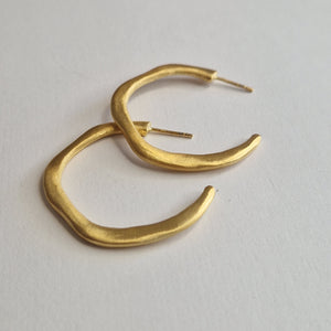 Gold hoop earrings on a light gray background