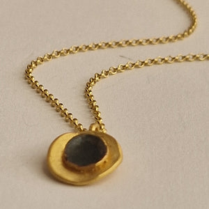 Gold necklace with a pendant on a beige background