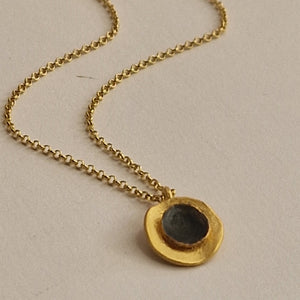 Gold necklace with a pendant on a beige background