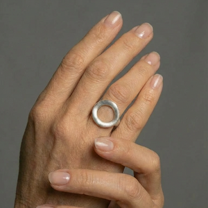 Hand wearing a silver ring on a gray background