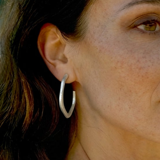 Woman with long dark hair and hoop earrings