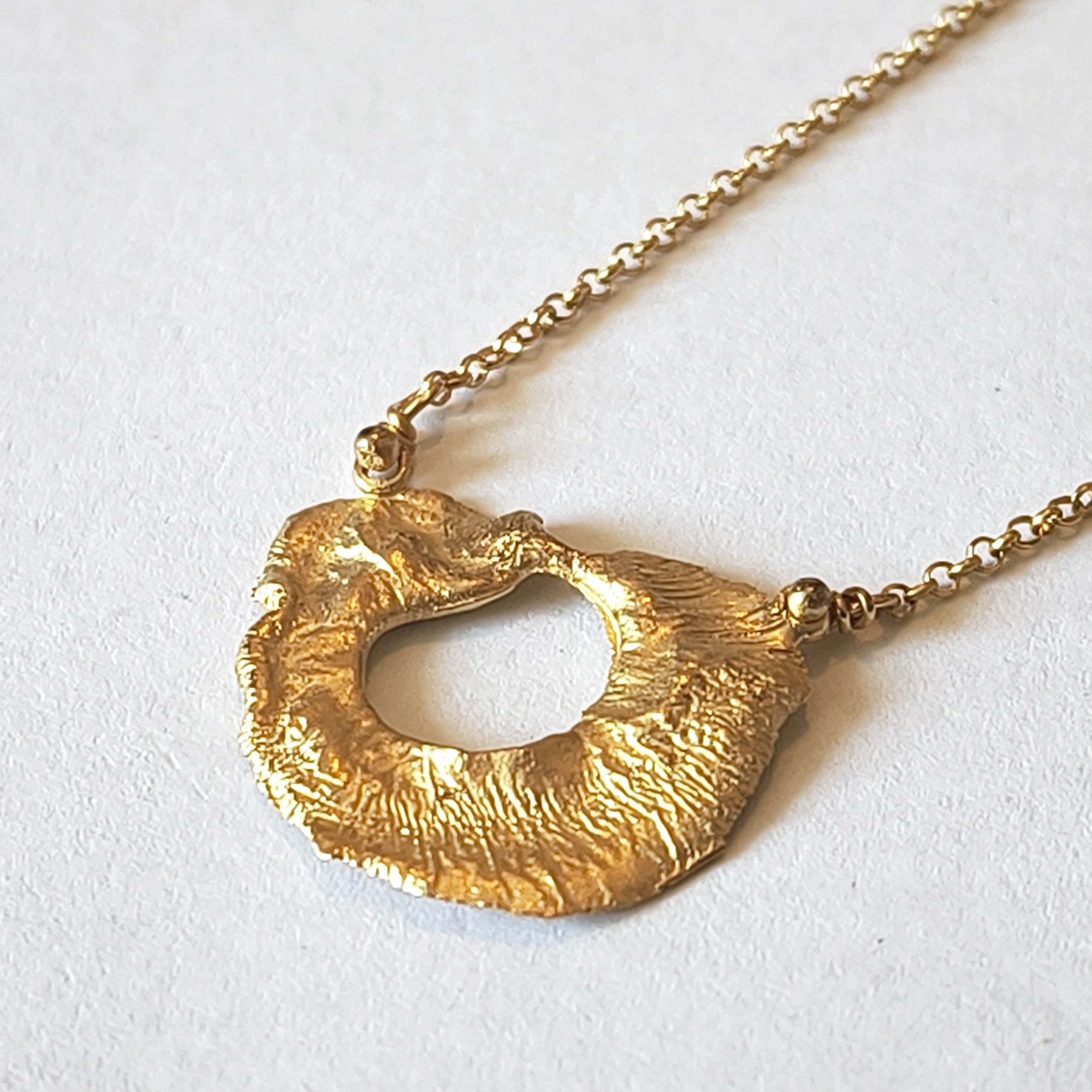 Close-up of VOLCANO textured matte gold plated sterling silver pendant