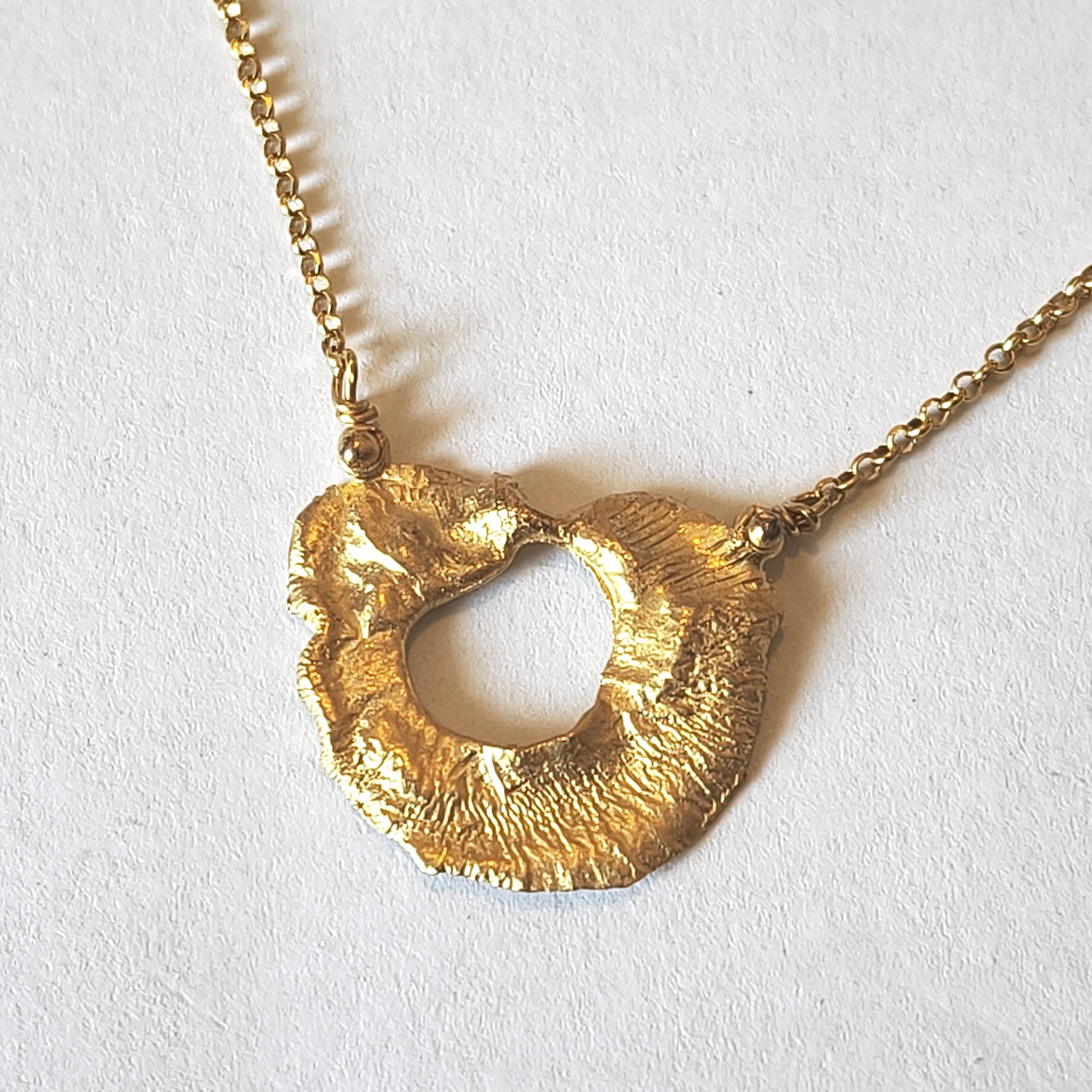 Close-up of VOLCANO textured matte gold plated sterling silver pendant